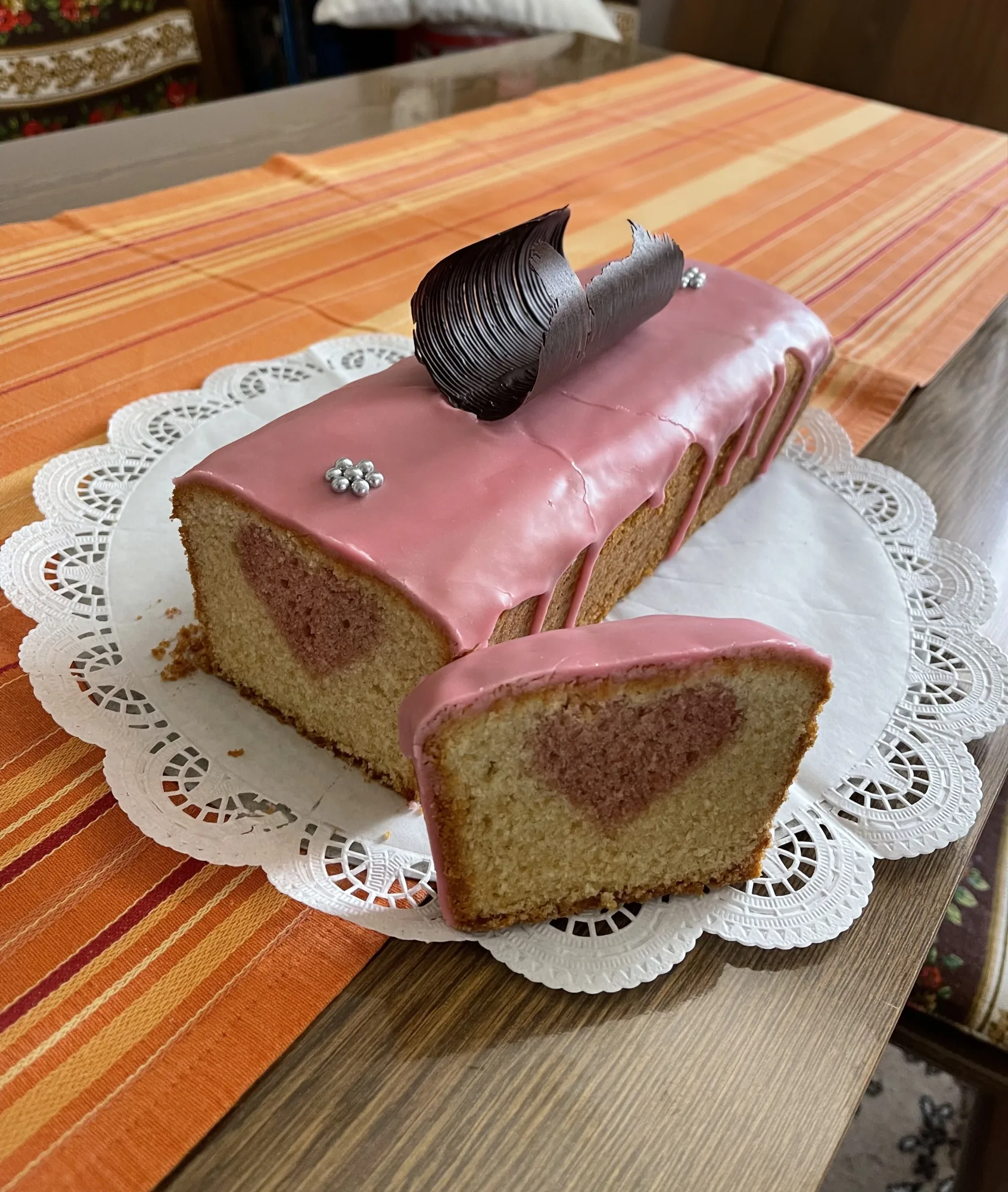 Kuchen mit verstecktem Herz: Rührkuchen mit rosa Glasur, Schokospan und Silberperlen, angeschnitten mit rosa Herz im Teig
