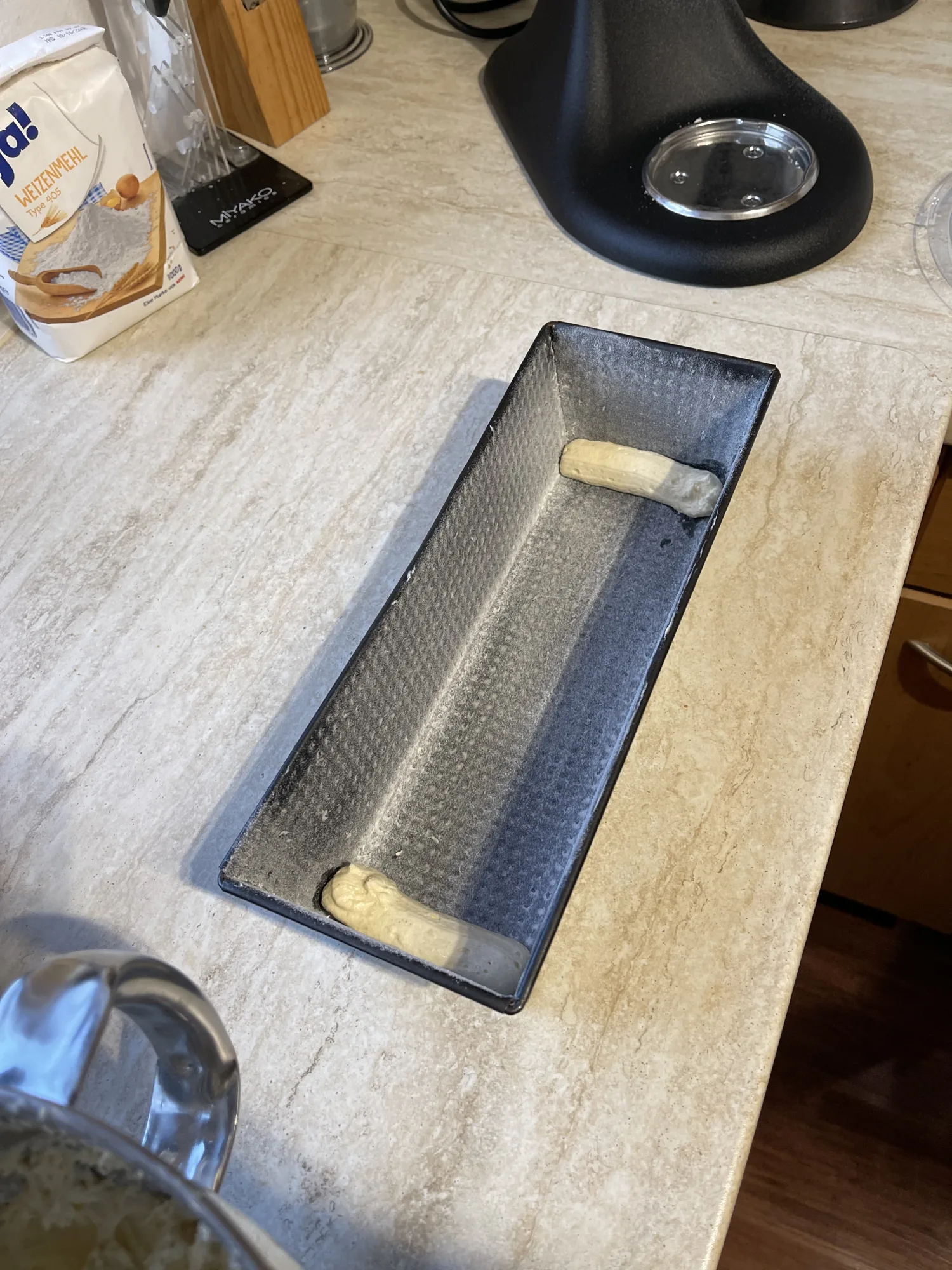 Mehlbestäubte Kastenform auf der Arbeitsplatte, an beiden Enden ein Teigstrang für den Kuchen mit verstecktem Herz