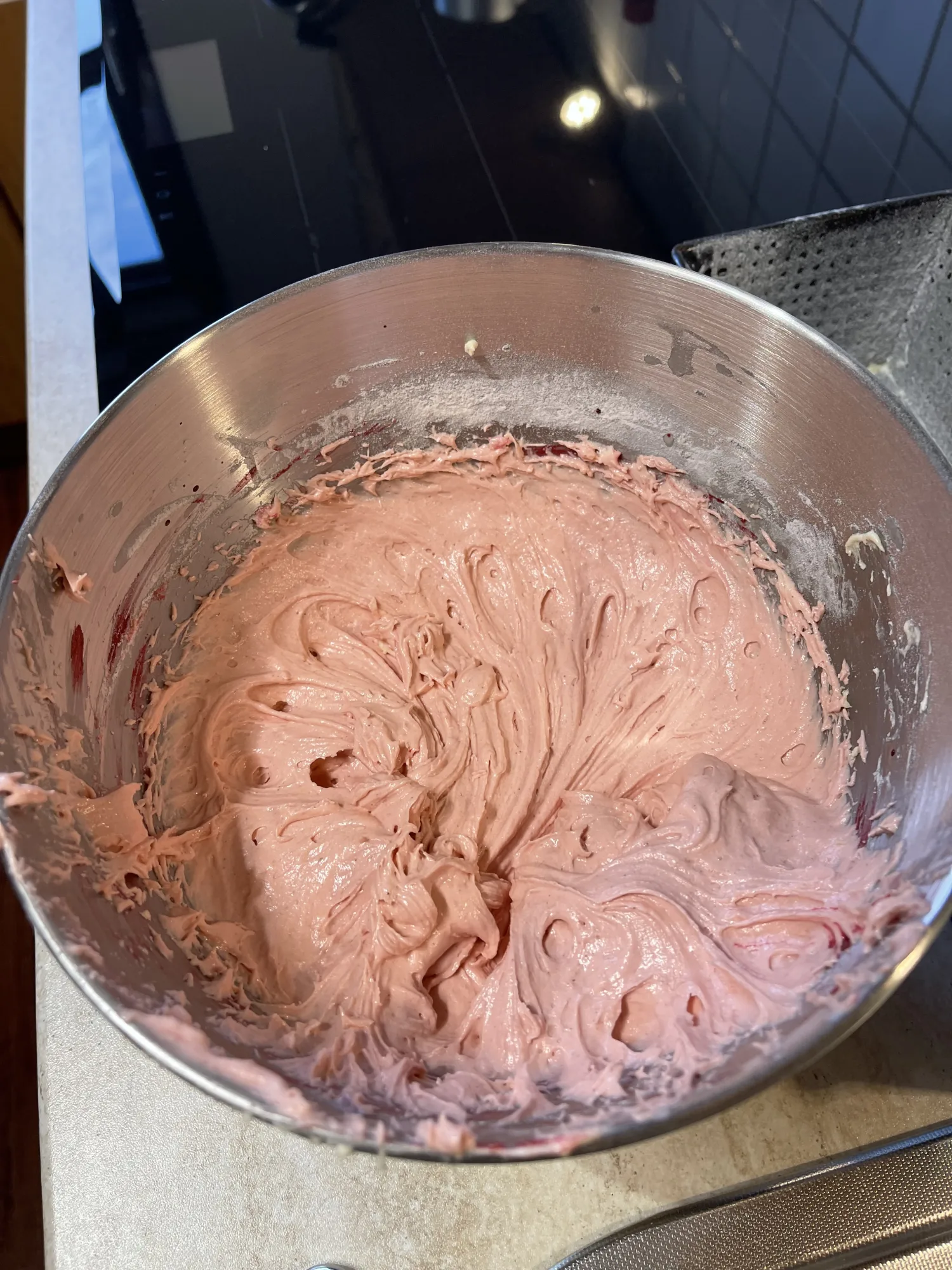 Rosafarbener, cremiger Rührteig für den Kuchen mit verstecktem Herz in einer Edelstahl-Rührschüssel auf der Arbeitsplatte