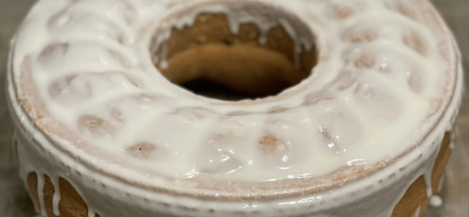 Selterskuchen as a ring-shaped bundt cake with white sugar glaze dripping down the golden-brown sides and into the center hole